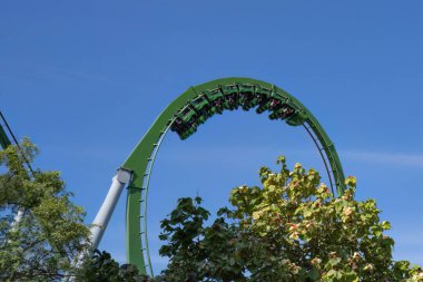 Güneşli bir günde lunaparkta hız treninde tepetaklak giden insanlar..