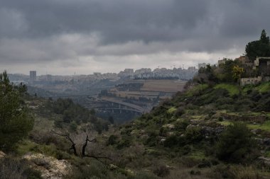 Kudüs, İsrail ve Judea dağları üzerinde fırtınalı, bulutlu, sisli bir kış günü. Badem ve çam ağaçları ve tarım terasları dağ yamaçlarını kaplıyor..