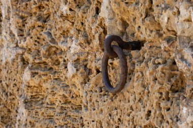 Atları güvence altına almak için paslı bir metal kravat yüzüğü, İsrail 'de eski bir kireçtaşı tuğla evin duvarına takılmış..
