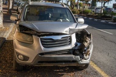Gri bir araba, araba kazasında hasar görmüş, sokağa park edilmiş..