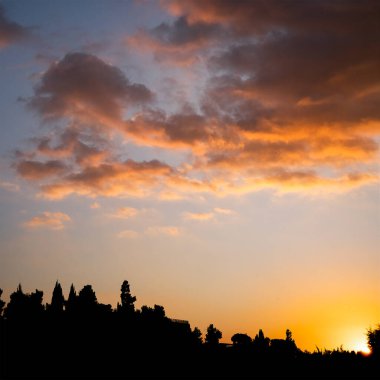 Güneş İsrail 'de bir kasabanın üzerinde kısmen bulutlu bir gökyüzünde batıyor..