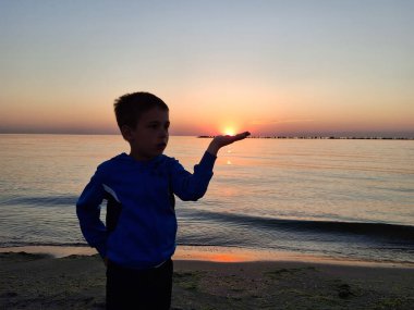 Bir çocuk ve güneş Karadeniz 'in üzerinde doğuyor. Mamaia 'da, Constanta
