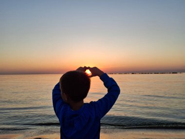 Bir çocuk ve güneş Karadeniz 'in üzerinde doğuyor. Mamaia 'da, Constanta
