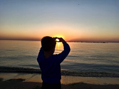 Bir çocuk ve güneş Karadeniz 'in üzerinde doğuyor. Mamaia 'da, Constanta