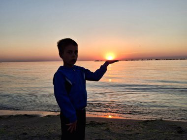 Bir çocuk ve güneş Karadeniz 'in üzerinde doğuyor. Mamaia 'da, Constanta