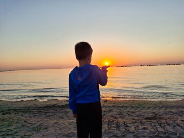 Bir çocuk ve güneş Karadeniz 'in üzerinde doğuyor. Mamaia 'da, Constanta