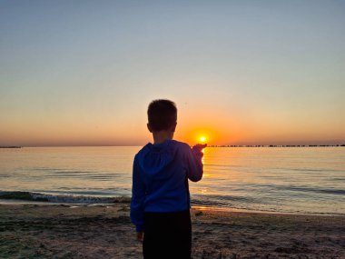 Bir çocuk ve güneş Karadeniz 'in üzerinde doğuyor. Mamaia 'da, Constanta