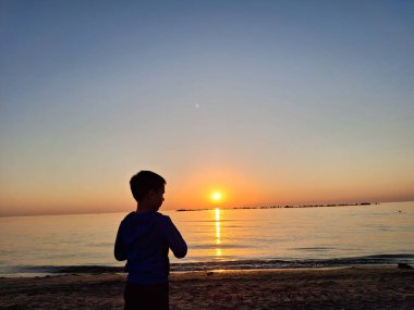 Bir çocuk ve güneş Karadeniz 'in üzerinde doğuyor. Mamaia 'da, Constanta