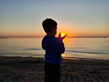 Bir çocuk ve güneş Karadeniz 'in üzerinde doğuyor. Mamaia 'da, Constanta