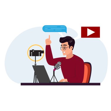 Gözlüklü genç adam bir masada oturuyor, bir dizüstü bilgisayar kullanıyor ve mikrofona konuşuyor. Önünde kamera var. Çal düğmesi 