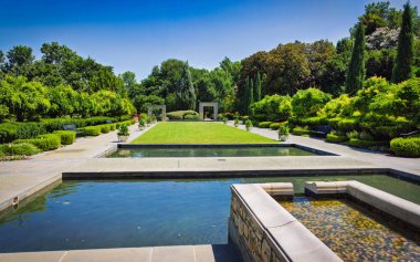 Havuzu ve çeşmesi olan büyük, sakin bir bahçe. Gölet ağaçlar ve çalılarla çevrilidir ve çeşme göletin ortasında yer almaktadır. Bahçe huzurlu.