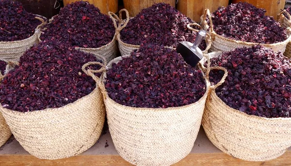 Close up of six handmade baskets full of crimson dried hibiscus flowers on market stall in Cairo, Egypt. A popular infusion at celebrations