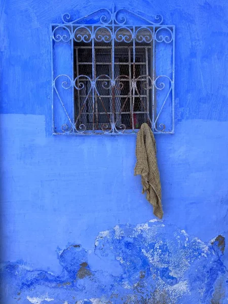 Grungy blue wall with cloth hanging from window, Chefchaouen, Morocco. High quality photo