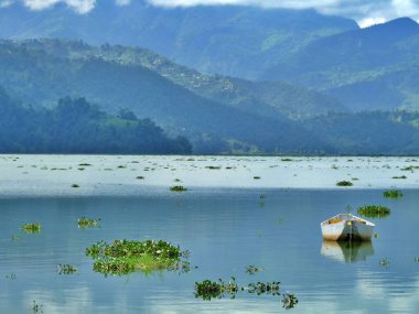 Suda ve dağlarda yüzen yalnız bir tekne, Fewa Gölü, Pokhara, Nepal. Yüksek kalite fotoğraf