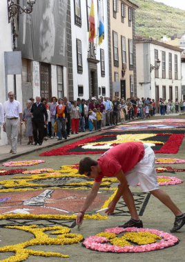 Corpus Christi, caddeleri çiçek halılarıyla kaplayarak kutlanır. Dini imgeler ve desenler, taze çiçekler ve farklı renklerde toprak tasvir edilir. 