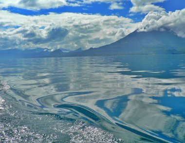 Blue waters of of Lake Atitlan Guatemala with volcano in background. High quality photo clipart