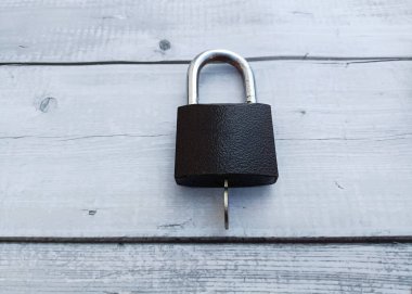 Black padlock on a white wooden background. The concept of security.