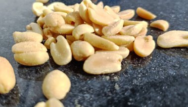 Peeled salted peanuts on a black background. Close-up.