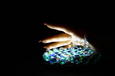 İnsan eli cam misketleri tutar beyaz siyah zeminde toplar, seçici odak