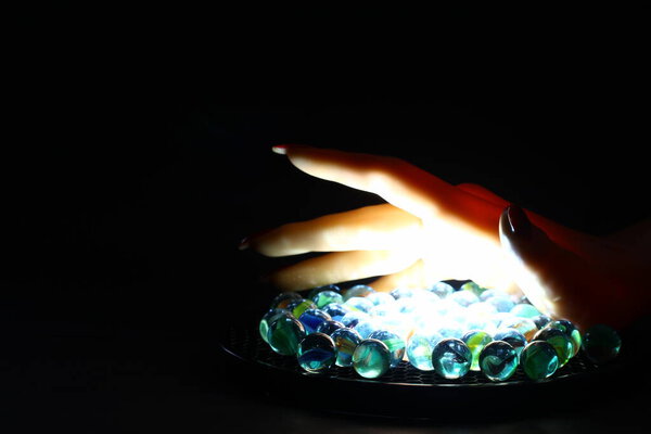 Человеческая рука держит стеклянные шарики мрамора на белом покрове, избирательный фокус