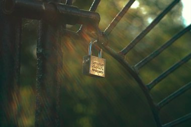 Çitteki zincirin üzerindeki metal kilit, arka plan bulanık.