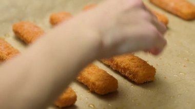 Balık kroket. Bir kadın fırındaki bir çarşafta kızarmak için balık kroket serer. Balık filetosu, yakın plan.