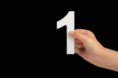 Siyah bir arka planda bir numara. Siyah arka planda bir numara, bir çocuk eli.