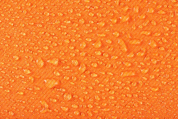 Waterproof clothing or upholstered furniture made from waterproof textiles. Drops of water on orange textiles with water-repellent properties