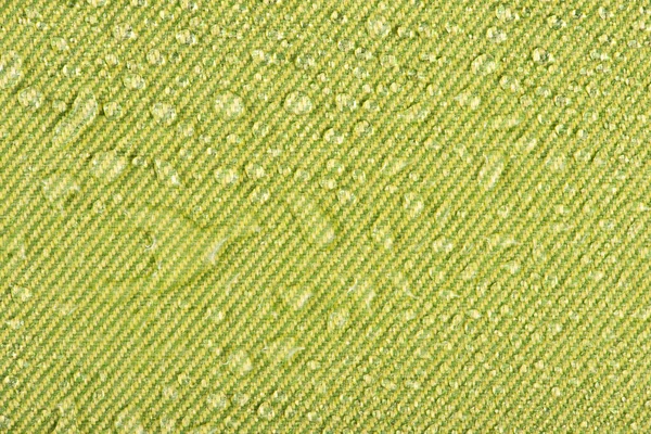 Waterproof clothing or upholstered furniture made from waterproof textiles. Drops of water on green textiles with water-repellent properties