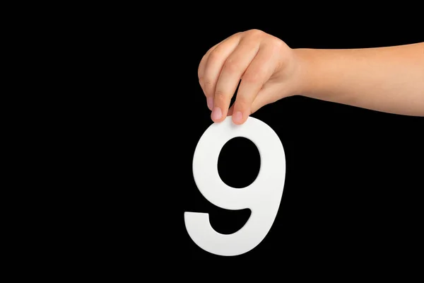 Number nine in hand isolated on black background. Number 9 in a childs hand on a black background. To be inserted into a project or design