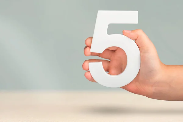 Νούμερο Πέντε Στο Χέρι Χέρι Κρατώντας Λευκό Αριθμό Θολή Φόντο — Φωτογραφία Αρχείου