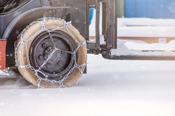 Cargo loader in winter on snow. The loader ride on snow with chains on the wheels to reduce slippage and spin. Driving safety in winter conditions.