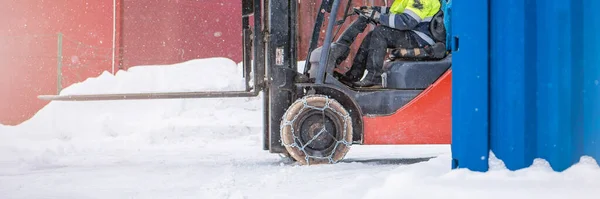 Cargo loader in winter on snow. The loader ride on snow with chains on the wheels to reduce slippage and spin. Driving safety in winter conditions.