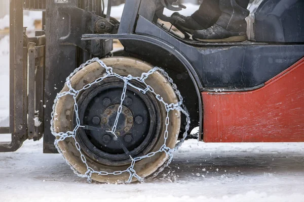 Tractor wheel with chain. Tractor or loader on a slippery snowy road. Loaders drive on snow with anti-skid chains