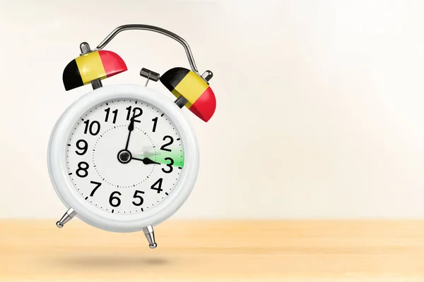Time change in Belgium, spring forward. Summer time concept, over white background. A white alarm clock with a minute hand indicates that the time has been moved forward an hour with copy space