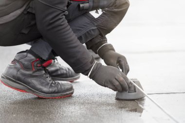 Yer kablosu. Bir işçi binanın çatısına kablo döşemiş. Elektrikçi güneş panellerini topraklamak için alüminyum kabloyu tamir ediyor.