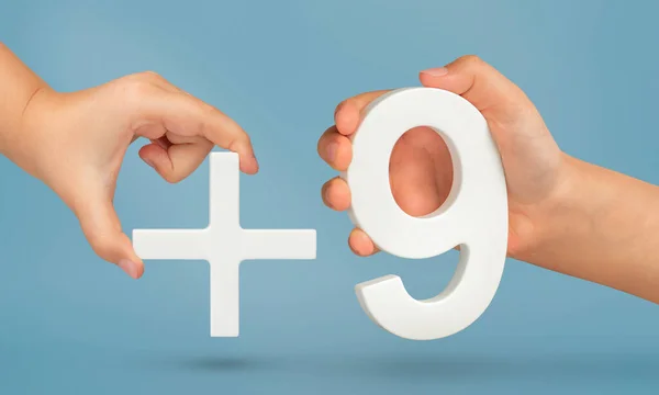 The number nine and the plus symbol in the hands of a child on a blue background. White number 9 with a plus close-up. The concept of addition or the sum of the number nine