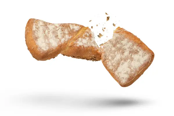 白面包上夹着一块脆面包 一块新鲜烘烤的脆面包被劈成两半 碎屑在休息时从四面八方飞散 新鲜烘焙的概念 底部的观点 高质量的照片 — 图库照片