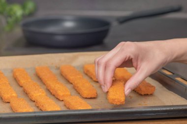 El, kızartma tavasının arka planına balık kroketi serer. Fırında balık kızartma kavramı. Yan görüş. Yüksek kalite fotoğraf