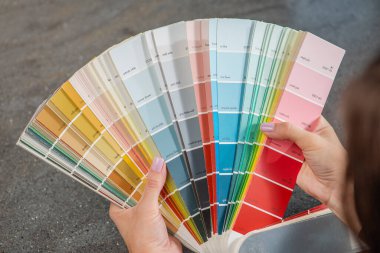 Ev tamiri. Duvar boyası rengi seçimi. Tasarımcı odayı boyamak için RAL paletinden bir renk seçer. RAL kataloğu bir kadının ellerinde. Yüksek kalite fotoğraf
