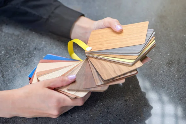 木材を模したラミネートのサンプル 女性デザイナーは積層床のサンプルを選択します 手の中の床サンプルを閉じる 高品質の写真 — ストック写真