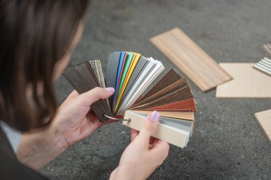 Tasarımcı, LMDP 'den mutfak mobilyası üretimi için pvc kenarı örnekleri seçiyor. Yakın plan kadın ellerinde çeşitli pvc kenarlı örnekler var. kopyalama alanı. Yüksek kalite fotoğraf