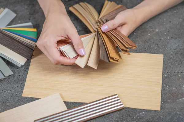 Tasarımcı, LMDP 'den mutfak mobilyası üretimi için pvc kenarı örnekleri seçiyor. Yakın plan kadın ellerinde çeşitli pvc kenarlı örnekler var. kopyalama alanı. Yüksek kalite fotoğraf