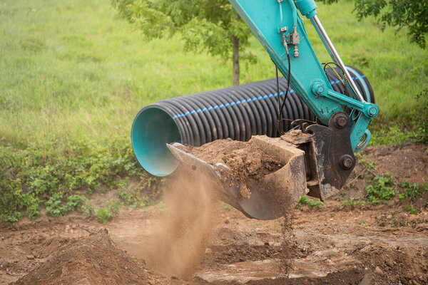 Процесс работы тяжелой строительной техники. Большой синий экскаватор засыпает землю в грузовик. Дорожные работы, реконструкция дорожного покрытия. Высокое качество фото