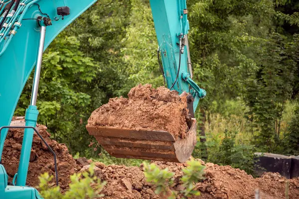 Construction of a new house. The excavator is clearing a place to build a house. Full bucket of earth close-up. High quality photo.