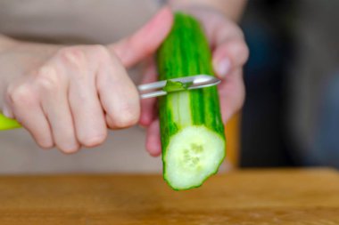 Salatalık soyan bir kadının elinin yakın çekimi. Salatalar için salatalık kabuğu soymak ya da sadece yemek için. Yüksek kalite fotoğraf. Yüksek kalite fotoğraf