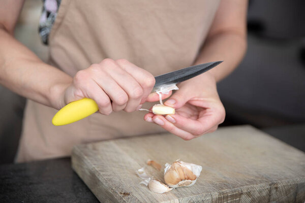 A woman cuts garlic with a knife close-up. Cutting garlic for salad or as an aromatic spice for meat. High quality photo