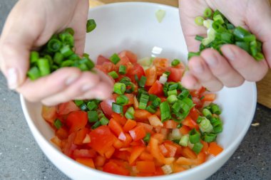 Salata hazırlama süreci. Bir kadının elleri, salataya doğranmış yeşil soğan dökerken. Yüksek kalite fotoğraf