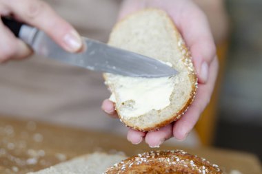 Kadın elinin bir dilim ekmeğe tereyağı sürdüğü yakın plan. Yürüyüş için hazır yemek ya da yemek yapmak için zamanın yoksa. Yüksek kalite fotoğraf