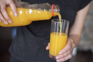 Bir kadın eli bardağa portakal suyu döker. Cama dökme işlemi. Yüksek kalite fotoğraf